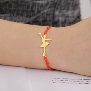 Detail of red braided rope bracelet with golden ballerina pendant on model wrist