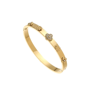 Gros plan détaillé d'un bracelet jonc doré poli avec des motifs floraux sertis de cristaux