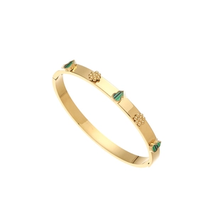 Detailed macro of a 18K gold-plated bangle with green heart inlays and beaded floral accents
