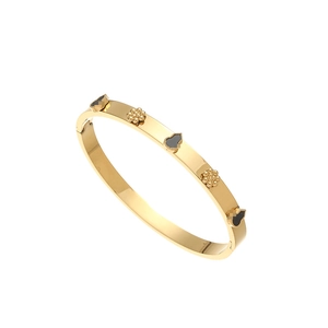 Detailed close-up of gold stainless steel bangle with black gourd and bead floral charms