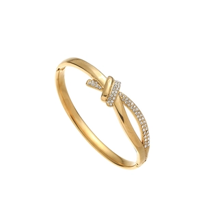Detailed view of gold knot bangle with white rhinestones and hinged closure mechanism