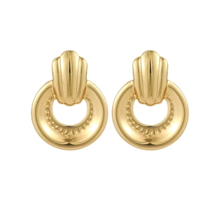 Détail de boucles d'oreilles dorées avec textures éventail et anneaux ciselés sur fond blanc