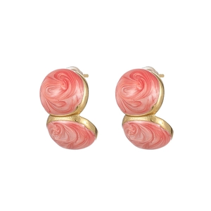 Detail of gold-plated C-shaped earrings with marble coral pink enamel inlay detail