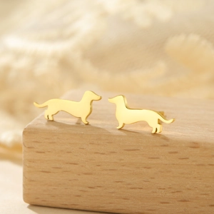 Pendientes de perro salchicha de acero inoxidable dorado sobre soporte de madera