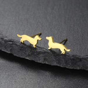 Detalle de pendientes de acero inoxidable con forma de dachshund dorado sobre piedra