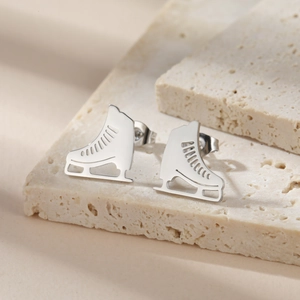 Polished silver ice skate stud earrings in stainless steel on a stone display