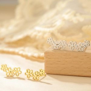 Vista macro di orecchini a lobo a fiore traforati in oro e argento su base di legno