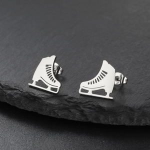 Detailed macro shot of ice skate shaped stainless steel earrings on a grey stone surface