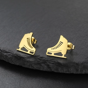 Macro shot of gold ice skate earrings on dark stone background with sharp metal details