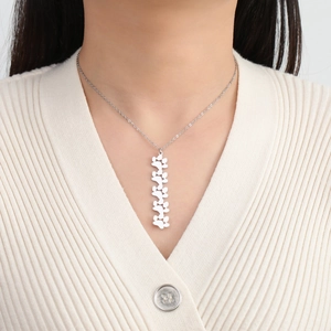 Primer plano de un collar de acero plateado con colgante de huellas en una modelo