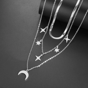 Collar de capas plateado con colgantes de estrella y luna sobre un elegante fondo negro