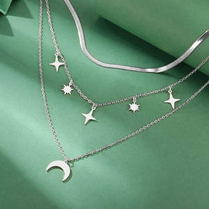 Detalle del collar de tres capas con colgantes de estrella y luna en acabado plateado