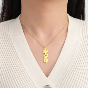 Primer plano de una modelo con un collar de acero dorado con cuatro colgantes de huella de gato
