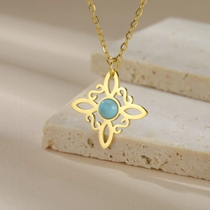 Detail of gold celtic knot necklace with light blue stone on minimalist stone background