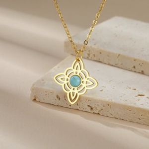 Detail of gold Celtic knot necklace with turquoise gemstone on stone surface