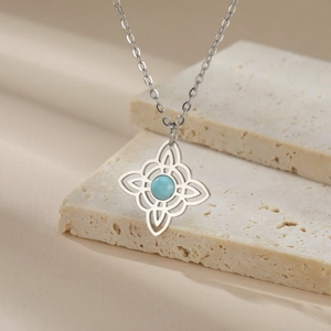 Detail of silver Celtic witch knot necklace with blue gemstone on beige stone