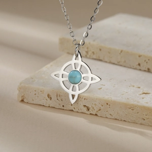 Detail of Celtic knot necklace with blue turquoise stone on beige stone surface