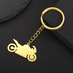 Polished gold motorcycle silhouette keychain made of stainless steel on dark stone background