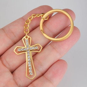 Golden titanium steel cross keychain with sparkling crystals held in hand