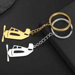 Detail of creative airplane keychains in gold and silver finish on textured black surface