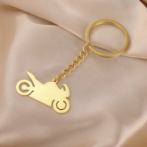 Detailed view of a gold-tone motorcycle silhouette keychain on a silk satin background