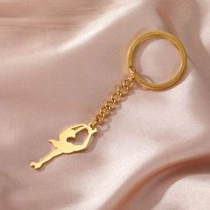 Détail d'un porte-clés doré silhouette de patineuse sur fond de soie champagne