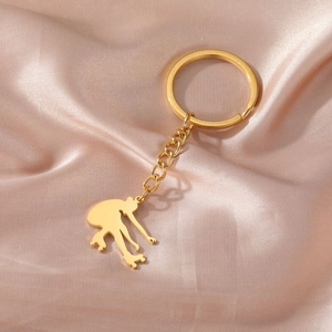 Porte-clés pendentif patineur doré poli sur un tissu élégant en satin champagne