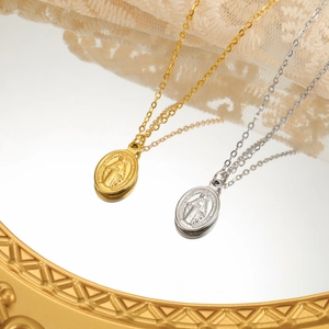 Elegant gold and silver oval Virgin Mary medallion necklaces with slim chains on a mirror