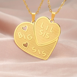 Close-up of gold stainless steel heart puzzle necklaces with Big Sis and Lil Sis engraving