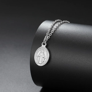 Detailed macro view of an oval Virgin Mary religious pendant on a fine silver chain