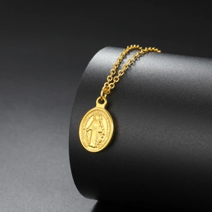 Detail shot of golden oval Virgin Mary religious pendant necklace on dark background