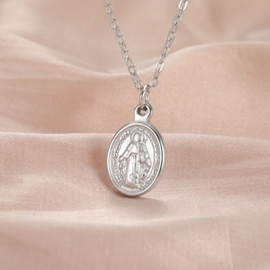 Macro shot of silver oval Virgin Mary medallion pendant on a delicate chain