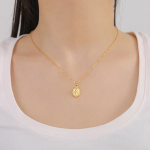 Close-up of a gold stainless steel necklace featuring a vintage oval Virgin Mary pendant