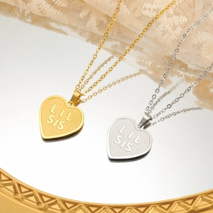 Close-up of gold and silver heart necklaces with Lil Sis engraving on a mirror