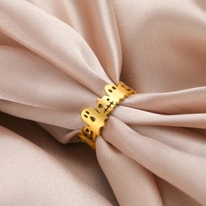 Detailed view of hollow ghost pattern on gold Halloween ring over champagne silk cloth