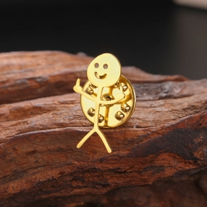Detail view of a funny gold stickman middle finger brooch on a wooden texture background