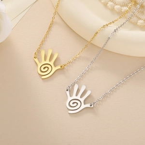 Unique spiral palm pendant necklace set in gold and silver tones on a minimal pedestal
