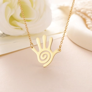Detail of gold palm pendant with spiral texture and polished stainless steel chain