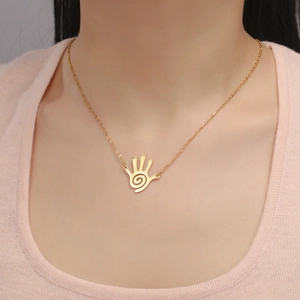Macro shot of gold stainless steel necklace with spiral palm pendant on a female model
