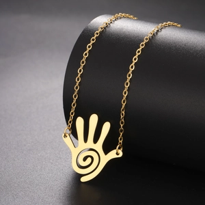 Detail of a golden spiral palm pendant necklace displayed on a black cylindrical stand