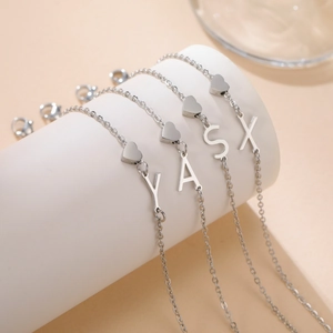 Detailansicht von vier Edelstahl-Armbändern mit Herz- und Buchstabenanhängern in Silber