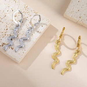 Pendientes de serpiente vintage en oro y plata con textura sobre soporte de piedra