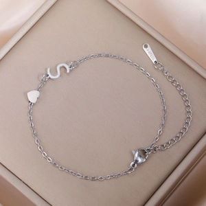 Detailaufnahme von Edelstahl S-Buchstaben und Herzanhänger-Armband mit Karabinerverschluss