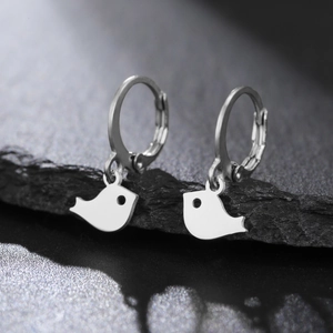 Vue macro d'un pendentif oiseau en argent sur une boucle d'oreille créole polie sur pierre