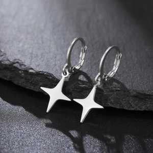 Detail of silver star dangle earrings displayed on a dark textured volcanic rock surface