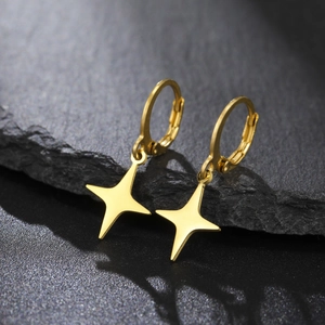 Detail of gold huggie hoop earrings with star pendants on dark stone background