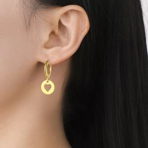 Élégantes boucles d'oreilles créoles dorées avec pendentif cœur portées par un mannequin