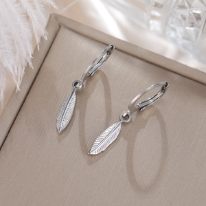 Vista detallada de pendientes de aro con pluma plateada en almohadilla de joyería