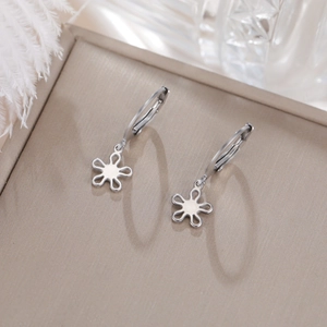 Détail de boucles d'oreilles créoles en acier argenté avec breloque fleur évidée