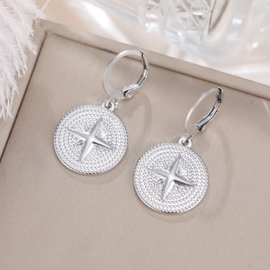 Primer plano de pendientes de aro plateados con estrella en una caja de regalo de lujo